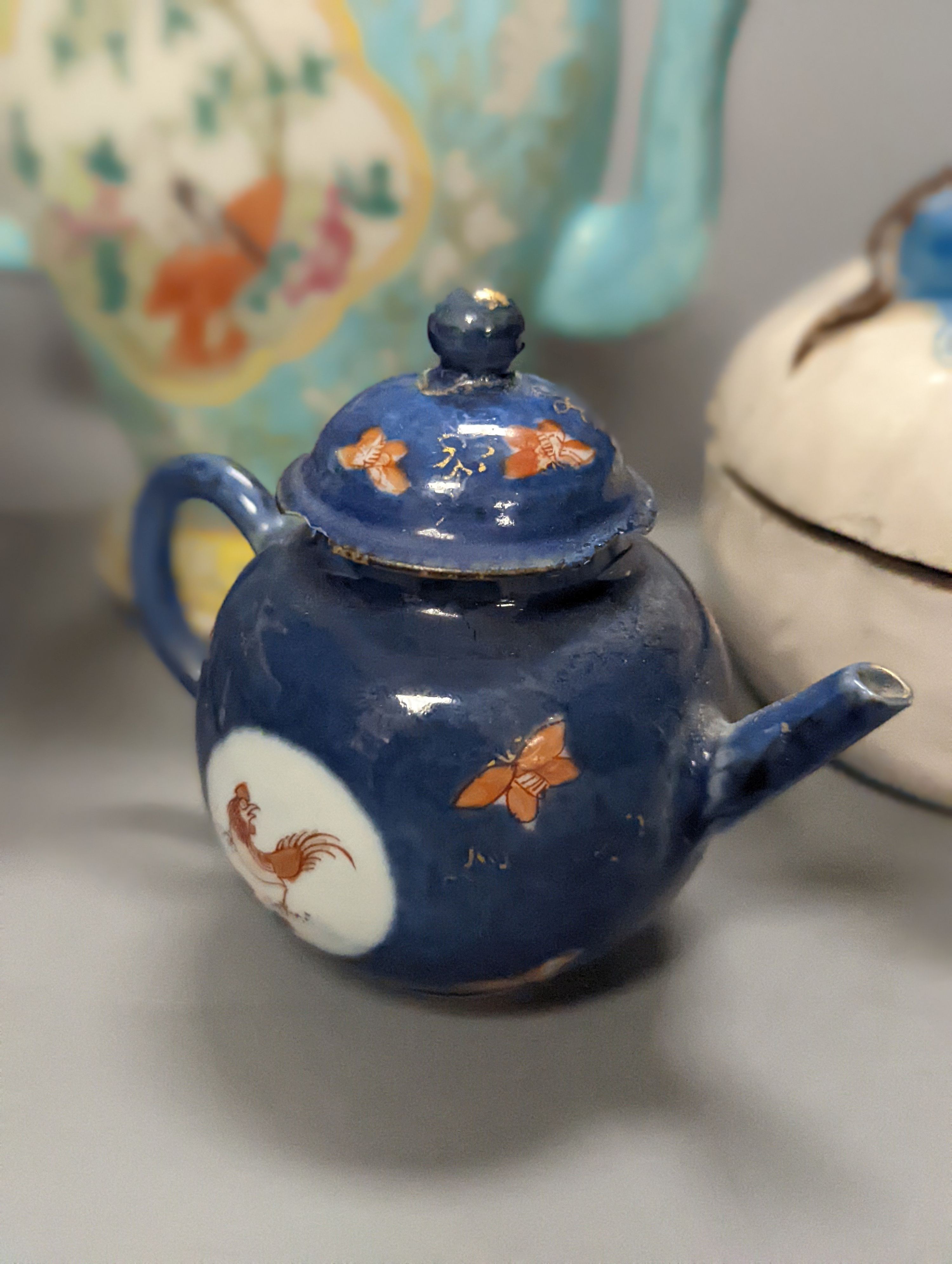 A 19th century Cadogan shape Chinese wine ewer, a Chinese blanc de chine figure riding an ox, an 18th century Chinese miniature blue ground ‘cockerel’ teapot and a Japanese Daikoku figural box and cover. Tallest 19cm